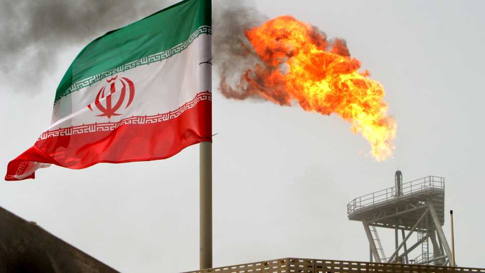 A gas flare on an oil production platform in the Soroush oil fields is seen alongside an Iranian flag in the Gulf.