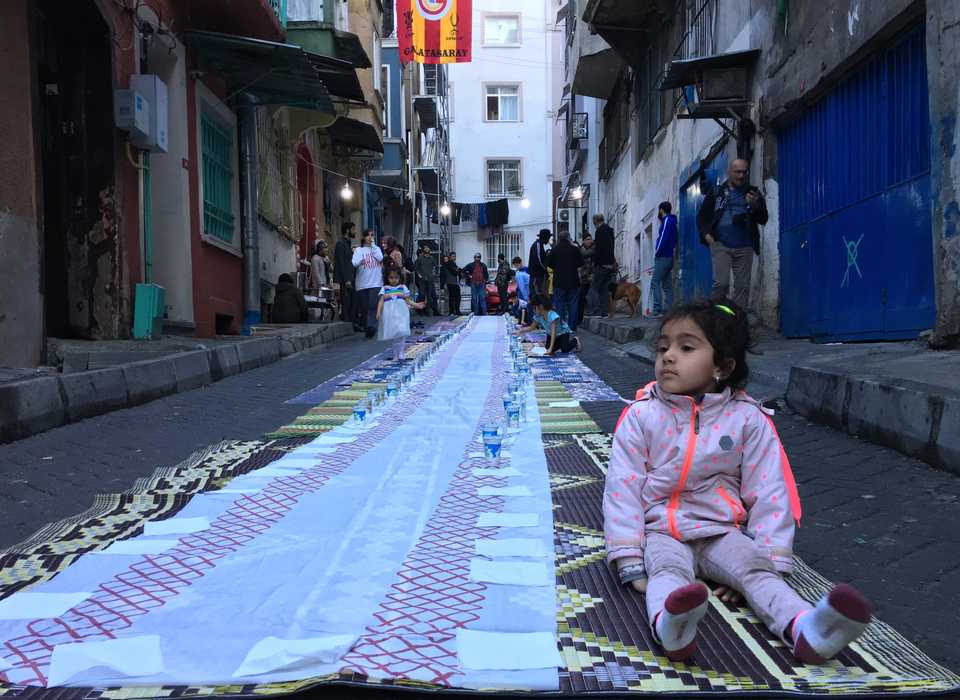 A young girl waiting while preparations are being made for iftar.