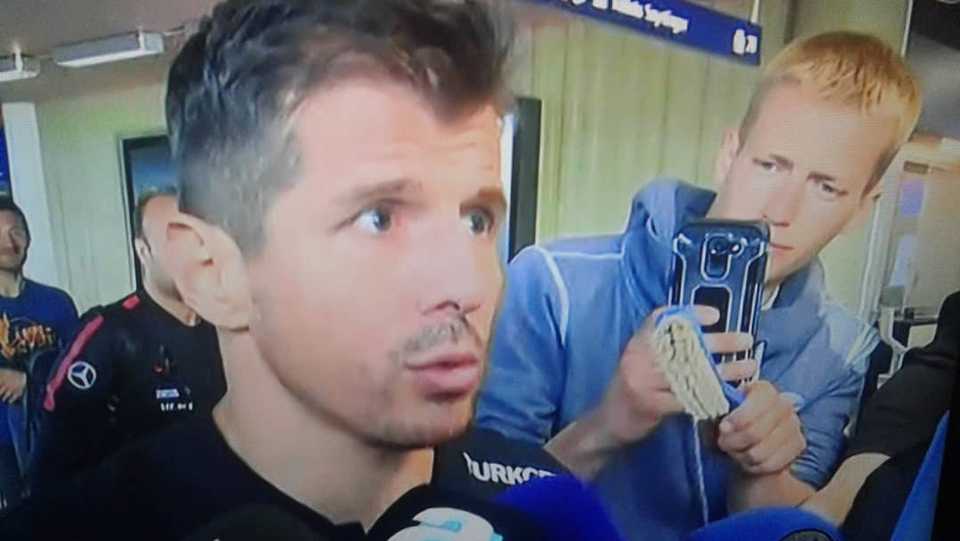The footage taken from a TRT Spor video shows an individual holding out a toilet brush to Emre Belozoglu while he was making a statement to the press.