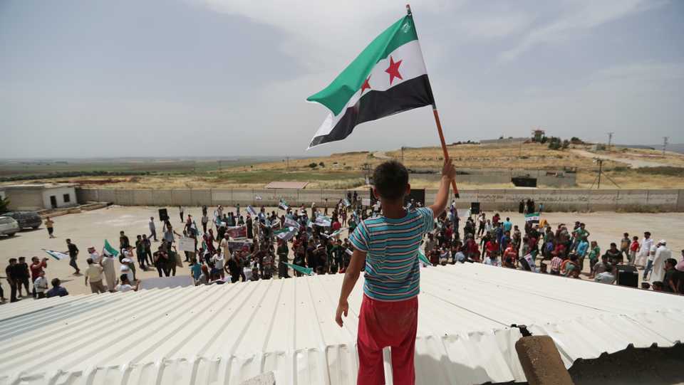 A boy holds the Free Syrian Army flag during a protest calling for an end to the strikes on the Syrian-Turkish border, in Idlib province, Syria, May 31, 2019.