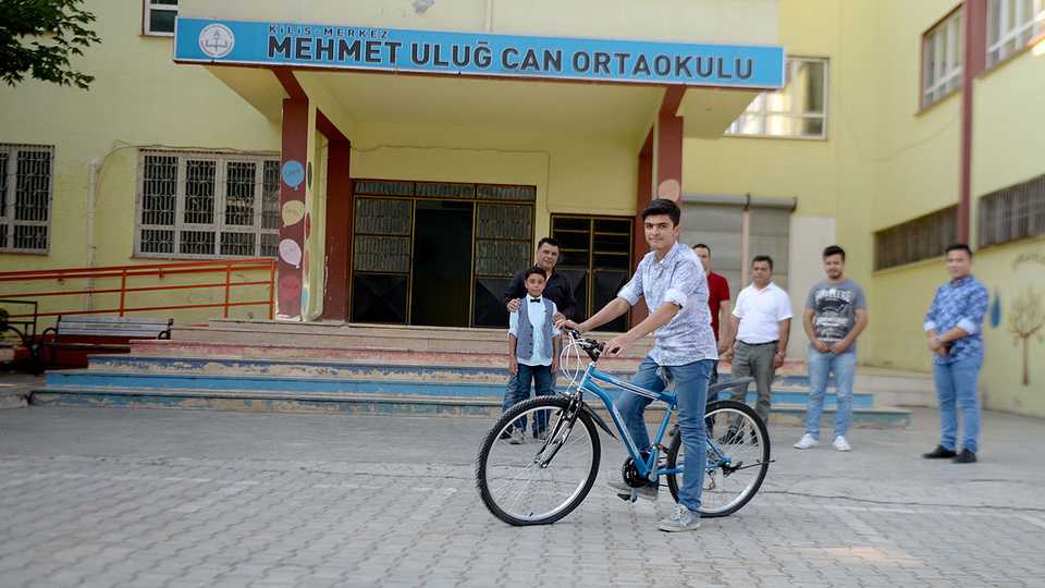 Syrian student Muhammet Halil in front of his school in Kilis's Mehmet Ulug Can Middle School where he got a bicycle gift for his success.
