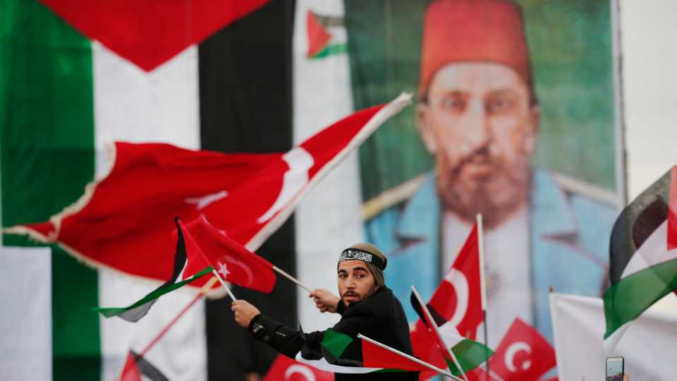 Backdropped by a Palestinian flag, left, and a picture depicting Abdul Hamid II, the last sultan of the Ottoman Empire, a protester participates in a rally against US President Donald Trump's decision to recognise Jerusalem as the capital of Israel, in Istanbul on Dec. 10, 2017.