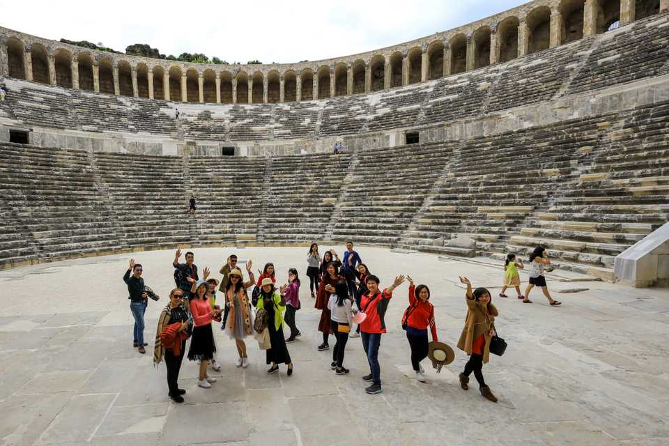 Tourists wave their hands as they pose for a photo at the Aspendos, an ancient Greco-Roman city in Antalya, Turkey on April 13, 2017. Aspendos and Perga are two of the most touristic places visited by Chinese tourists.