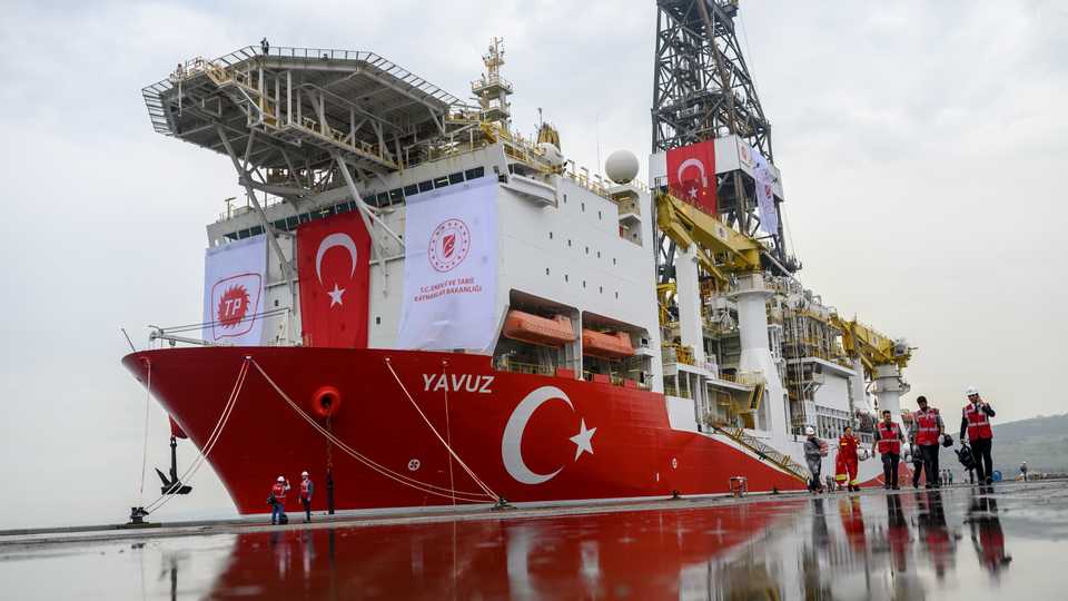 In this file photo taken on June 20, 2019 journalists walk next to the drilling ship 'Yavuz' employed to search for oil and gas off Cyprus, at the port of Dilovasi, outside Istanbul.