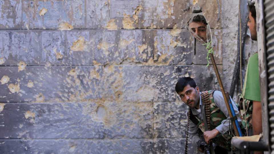 A Free Syrian Army fighter (R) looks through a mirror which helps him see Syrian regime forces from the other side, as he takes his position with his comrade during fighting, at the old city of Aleppo city, Syria. September 24, 2012.