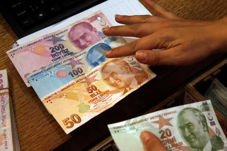 A worker at a currency exchange shop exhibits Turkish lira banknotes bearing pictures of modern Turkey's founder Mustafa Kemal Ataturk, in Istanbul on Aug. 15, 2018.