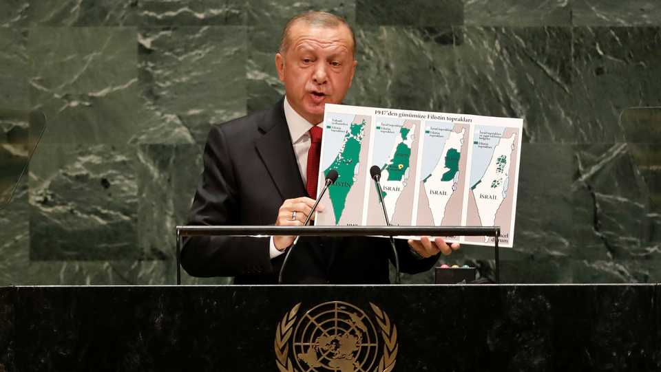 Turkish President Recep Tayyip Erdogan holds a picture that shows how Israel has occupied Palestinian territories over the years.