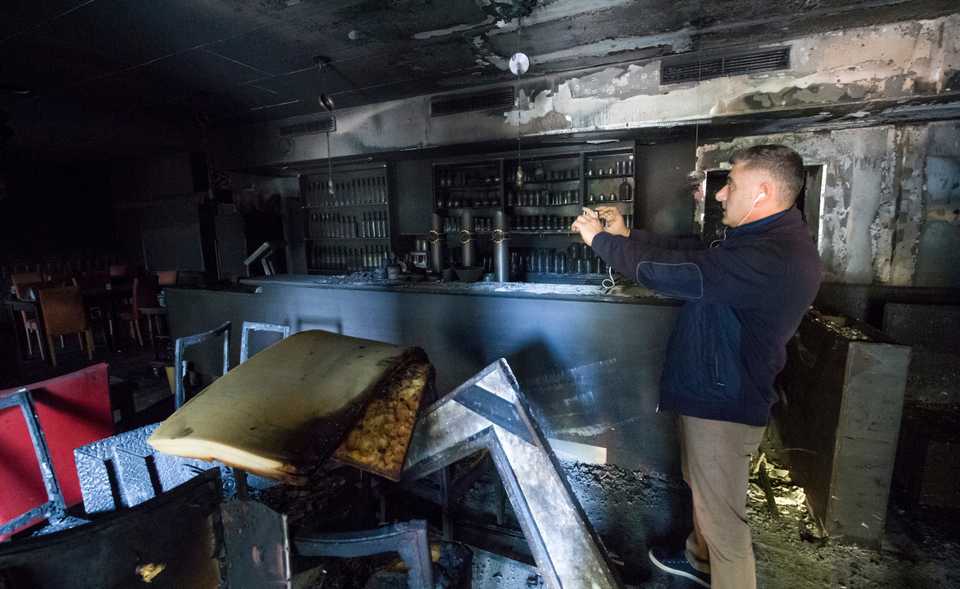 Ali Tulasoglu takes a photo of his Turkish restaurant after it is burn out in the easter German town of Chemnitz, Thursday, Oct. 18, 2018. (Hendrik Schmidt/dpa via AP)