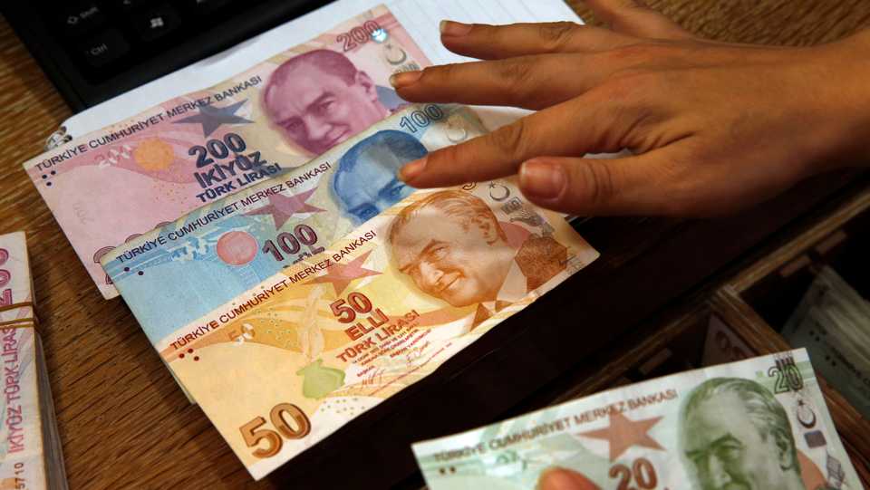 In this August 15, 2018 file photo, a worker at a currency exchange shop exhibits Turkish lira banknote in Istanbul.