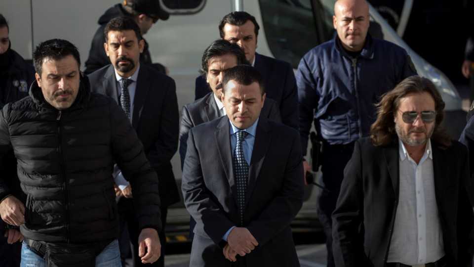 Four of the eight Turkish soldiers (C) who fled to Greece in a helicopter line up as they are escorted by police at the Supreme Court in Athens on January 13, 2017. 