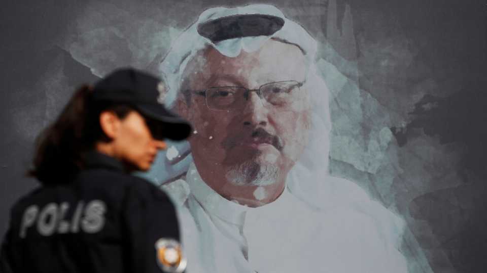 In this October 2, 2019 file photo, a Turkish police officer walks past a picture of slain Saudi journalist Jamal Khashoggi near the Saudi Arabia consulate in Istanbul.