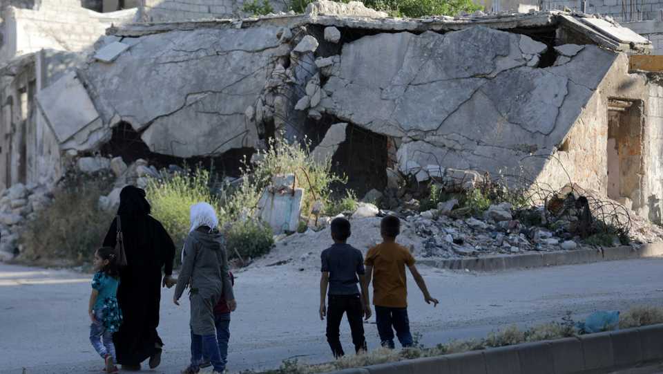 People walk near rubble of damaged buildings in the city of Idlib, Syria, May 27, 2019.