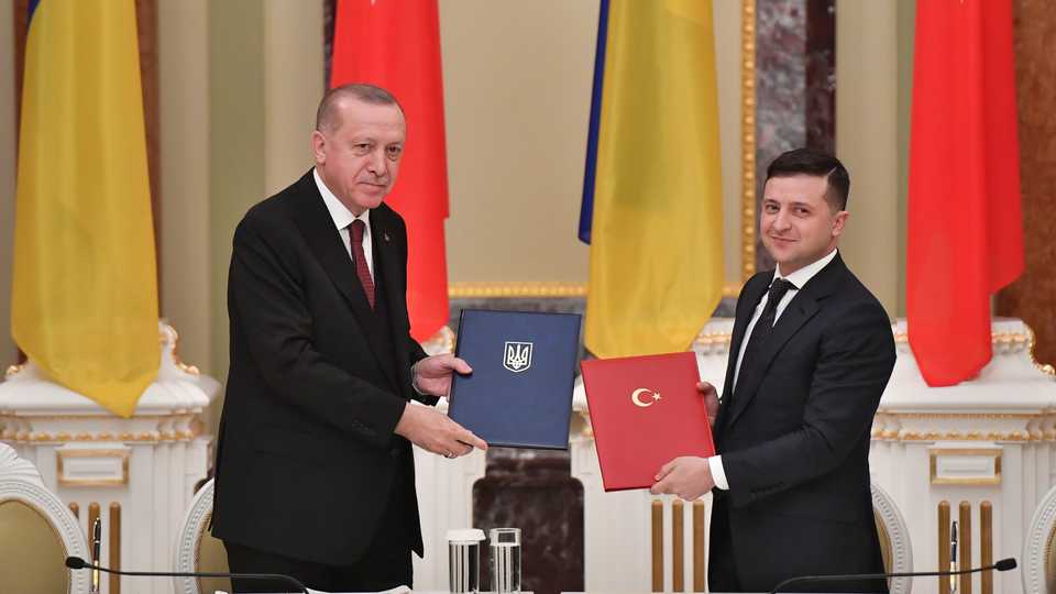 Ukrainian President Volodymyr Zelenskiy and his Turkish counterpart Recep Tayyip Erdogan exchange documents during a signing ceremony following their meeting in Kiev on February 3, 2020.