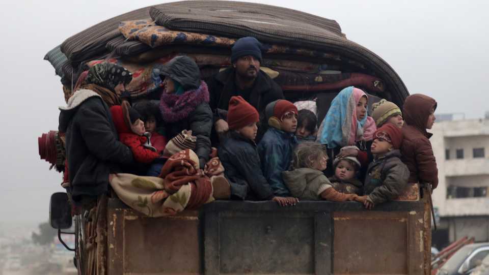 Internally displaced Syrians from western Aleppo countryside, ride on the back of a truck with belongings in Hazano near Idlib, Syria, February 11, 2020.