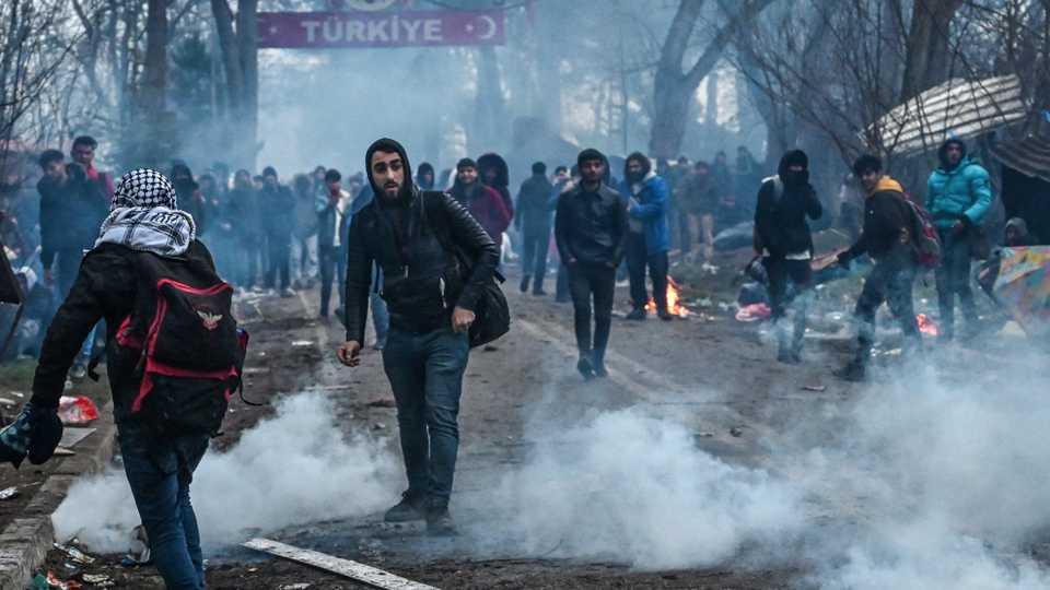 Migrants run away as Greek anti riot police officers use tears gas on the buffer zone Turkey-Greece border, at Pazarkule, in Edirne district, on February 29 , 2020.