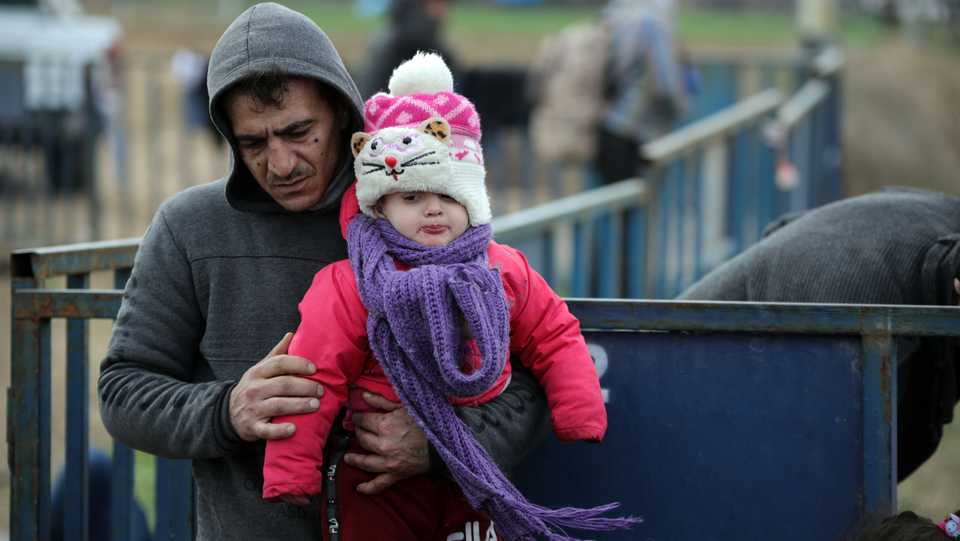 A man carries his daughter who is bundled up against harsh winter conditions at the border between Turkey and Greece in Edirne, Turkey.