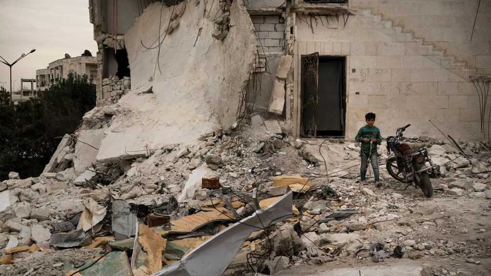 A boy walks out of a heavily damaged building, where he is currently living, in Idlib, Syria on March 12, 2020.