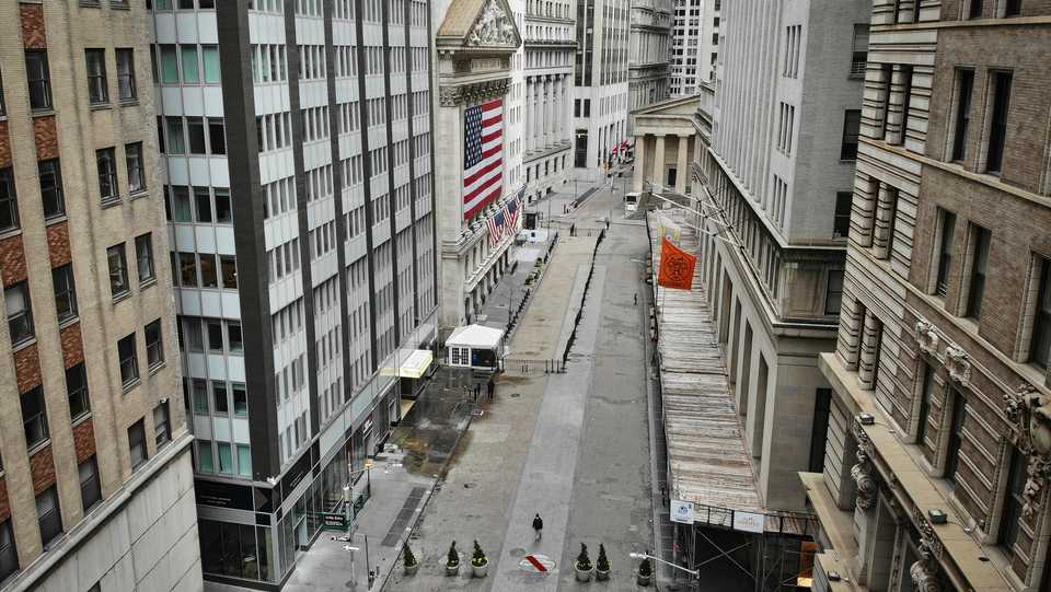 A lone pedestrian wearing a protective mask walks past the New York Stock Exchange as Covid-19 concerns empty a typically bustling downtown area, Saturday, March 21, 2020, in New York