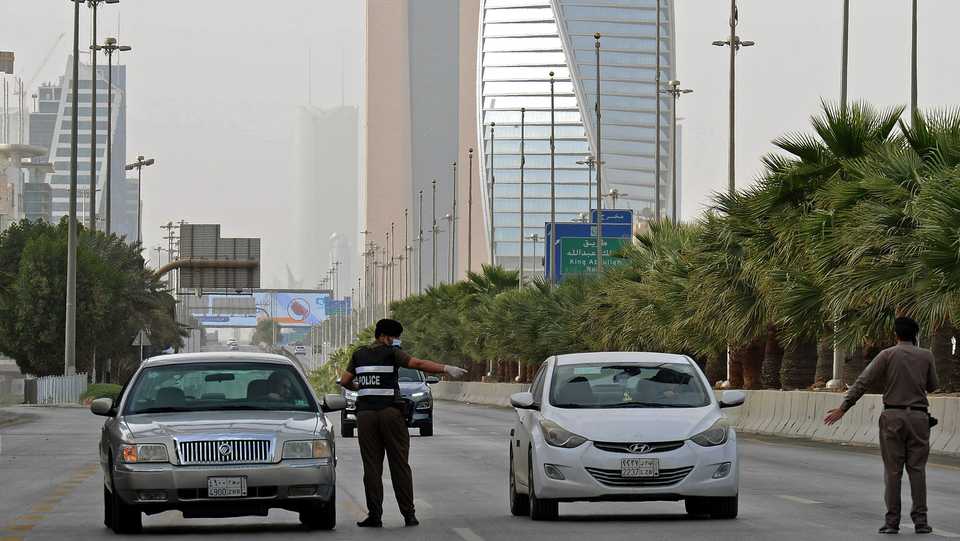 A picture taken on March 26, 2020, shows Saudi policemen manning a checkpoint in the King Fahad main street in the capital Riyadh, after the Kingdom began implementing a nationwide curfew.