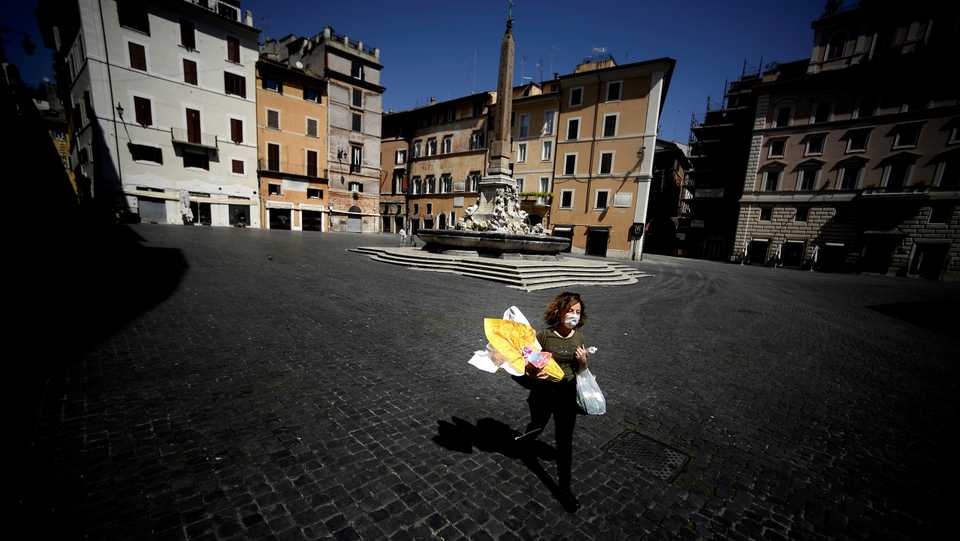 A woman carries her shopping and an Easter egg across Piazza della Rotonda in central Rome, on April 11, 2020 during the country's lockdown.