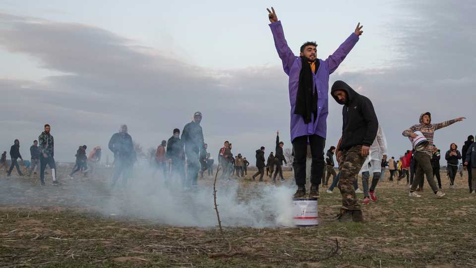 A migrant reacts while others stand near a cloud of tear gas as they gather on the Turkish-Greek border near Turkey's Pazarkule border crossing with Greece's Kastanies, in Edirne, Turkey March 7, 2020.
