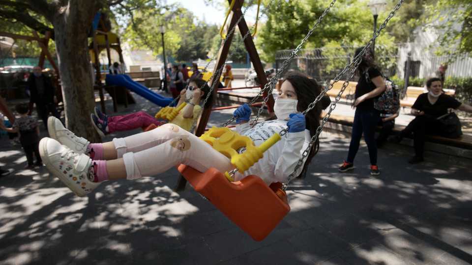 Children wearing face masks for protection against the coronavirus, play on swings in Kugulu public garden, in Ankara, Turkey, Wednesday, May 13, 2020.