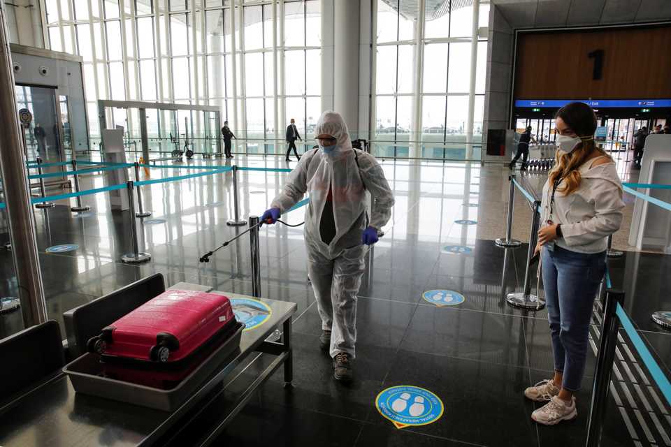 An employee wearing a protective suit disinfects luggage at the Istanbul Airport during the first day of resumed domestic flights, which were halted since March 26 amid the coronavirus outbreak, in Istanbul, Turkey, June 1, 2020.