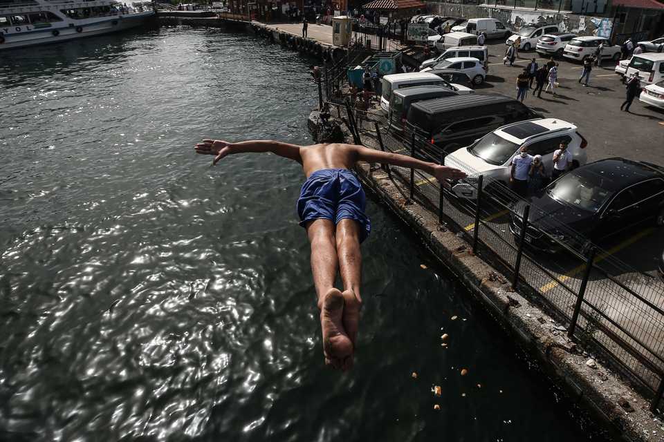 A boy jumps into the sea during the first weekend without novel coronavirus pandemic restrictions since April 10, off of Galata Bridge in Istanbul, Turkey on June 06, 2020.