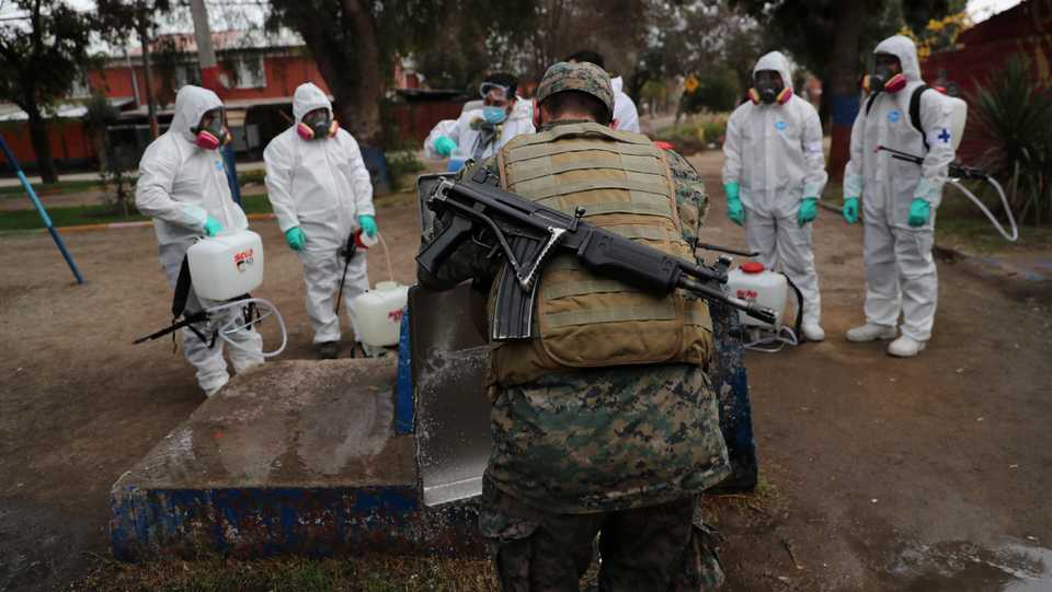 An army member washes a tray as comrades get ready to apply disinfectant before a food delivery in a socially vulnerable community following the coronavirus outbreak in Maipu area at Santiago, Chile, June 16, 2020.