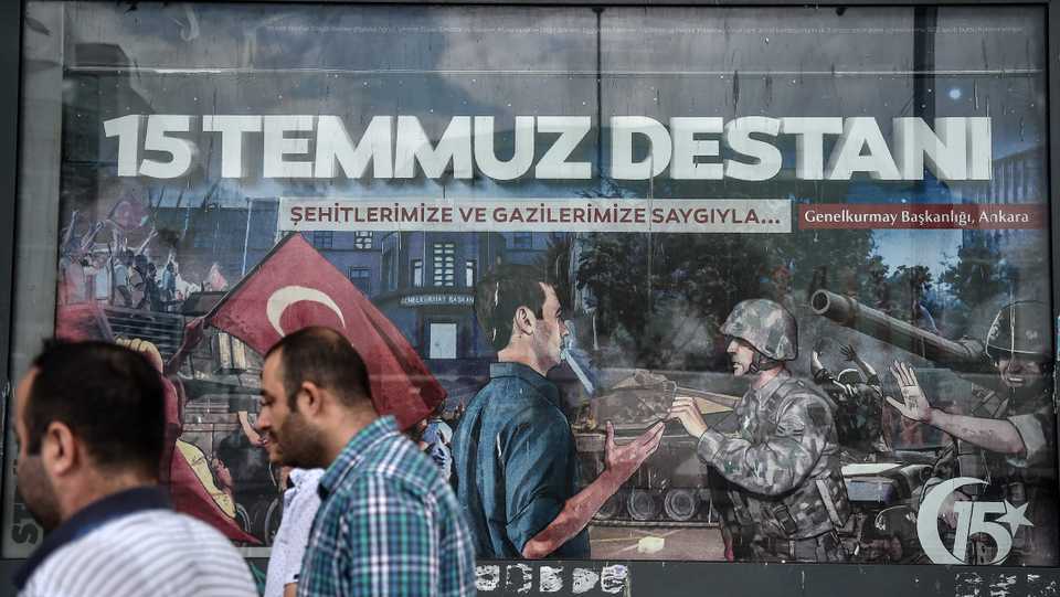 In this file photo taken in Istanbul on July 14, 2017, people walk past a giant billboard reading 