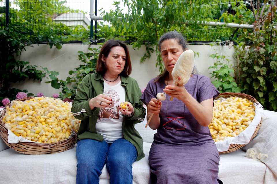 Berna Ileri (L) and Emine Duman with empty Hatay yellow cocoons and a spindle.