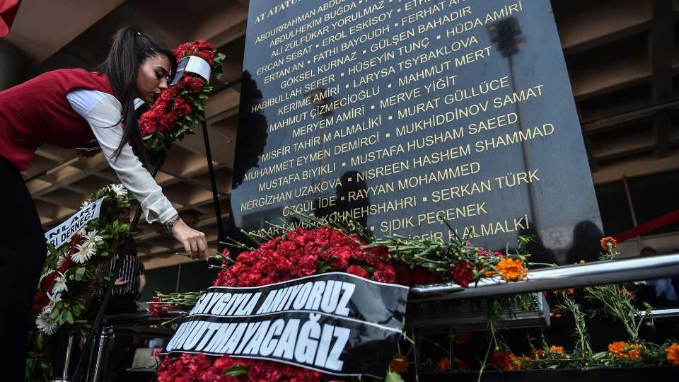 An airport employee lays a flower by a commemorative plaque during a memorial ceremony at Ataturk International airport in Istanbul on June 28, 2017.
