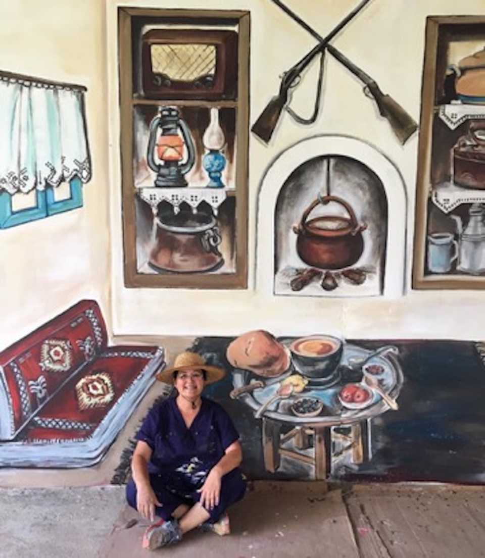 Nazife Bilgin Hazar sits in front of a mural she painted for the Alzheimer’s Foundation in Mersin.