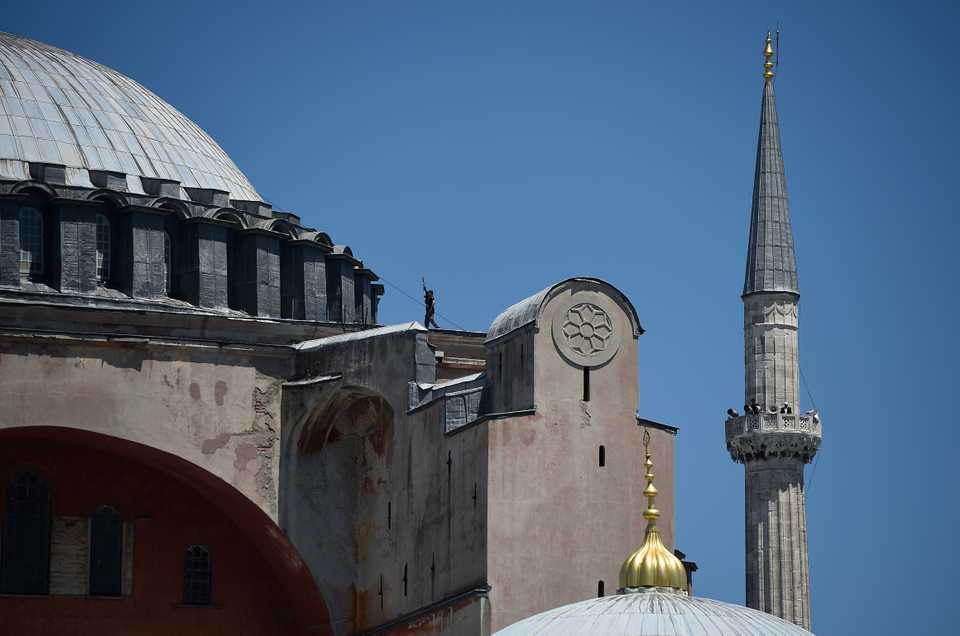 A Turkish police officer walks with his gun on the dome as a muezzin calls for Friday prayers on a minaret of Hagia Sophia in Istanbul, Turkey, July 24, 2020.