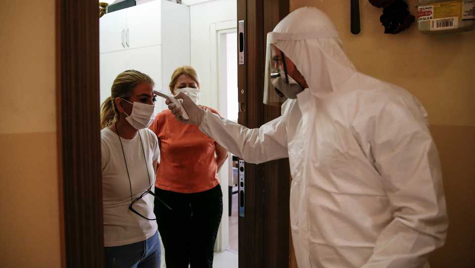 Turkey's Health Ministry's coronavirus contact tracing team swabs Betul Sahbas, left, who had been experiencing Covid-19 symptoms, to take a sample at her home in Istanbul, May 15, 2020.