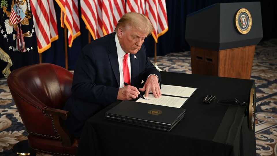 President Donald Trump signs executive orders extending coronavirus economic relief during a news conference at his golf club in Bedminster, New Jersey, on August 8, 2020.