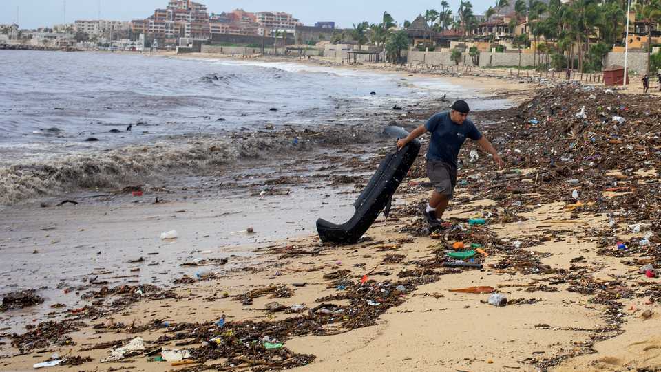 A man removes debris on the beach after the crossing of Hurricane Genevieve in Cabo San Lucas, Mexico's Southern Baja Peninsula, August 20, 2020.
