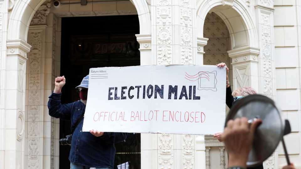 Demonstrators hold a large mock mail-in ballot as others hit pans and pots during a protest against changes in the postal service outside of the condo of Postmaster General Louis DeJoy in Washington, US, August 15, 2020.