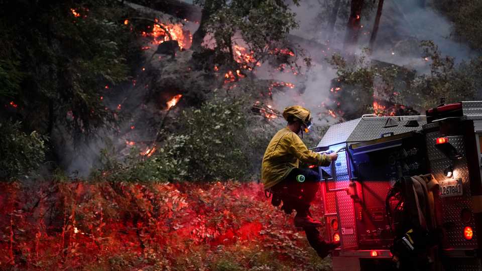 A firefighter for the Boulder Creek Fire Department, gets down from a fire truck, August 22, 2020, in Boulder Creek, California.