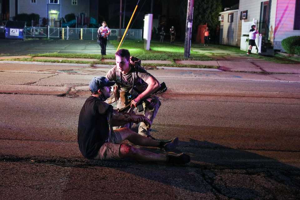 An armed man is seen tending to another man, who appears to have been wounded after clashes between armed civilians in Kenosha, Wisconsin where crowds had gathered to protest the police shooting of a Black man. August 26, 2020.