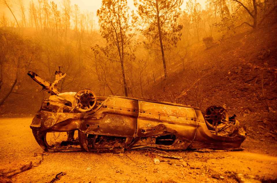 The charred remains of a vehicle is left on the side of a road during the Bear fire, part of the North Lightning Complex fires, in unincorporated Butte County, California.