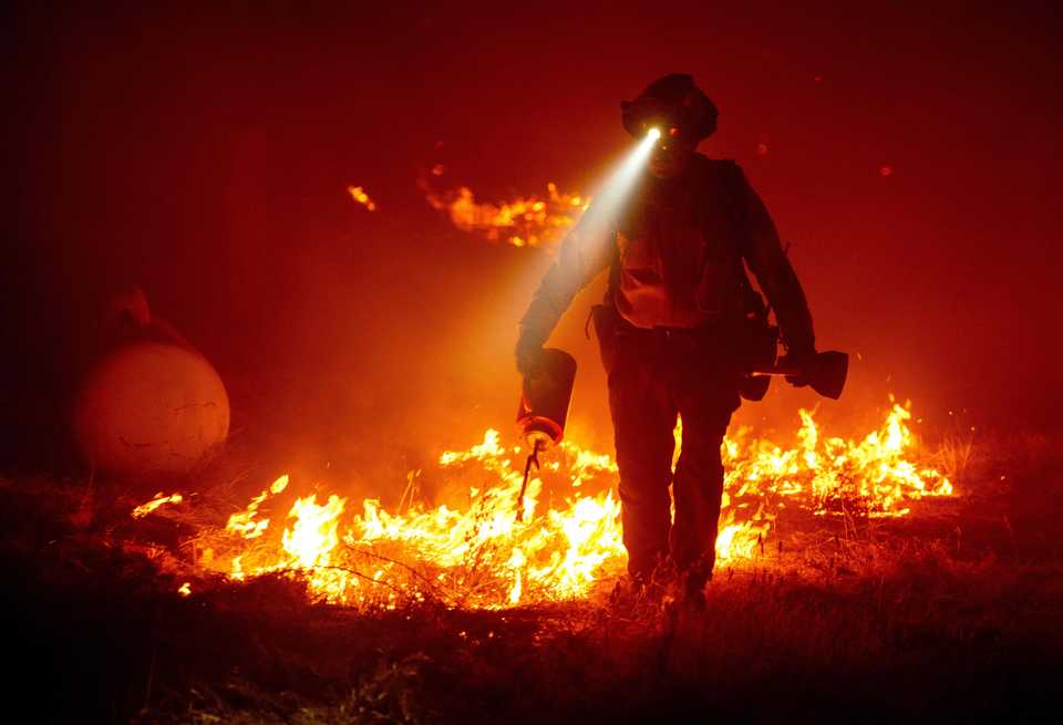 Firefighters cut defensive lines and light backfires to protect structures behind a CalFire fire station during the Bear fire, California.