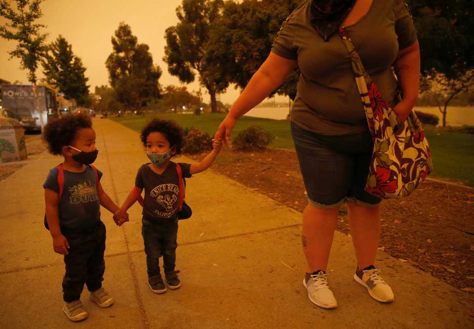 Emory and Henry Peters, 2, walk with their nanny Cynthia Chavez at Lake Merritt in Oakland, Calif., on Wednesday, Sept. 9, 2020.