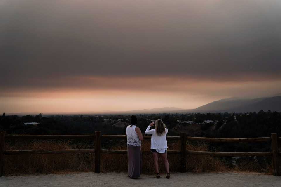Two spectators watch smoke generated by the Bobcat Fire in San Dimas, Calif., Wednesday, Sept. 9, 2020.