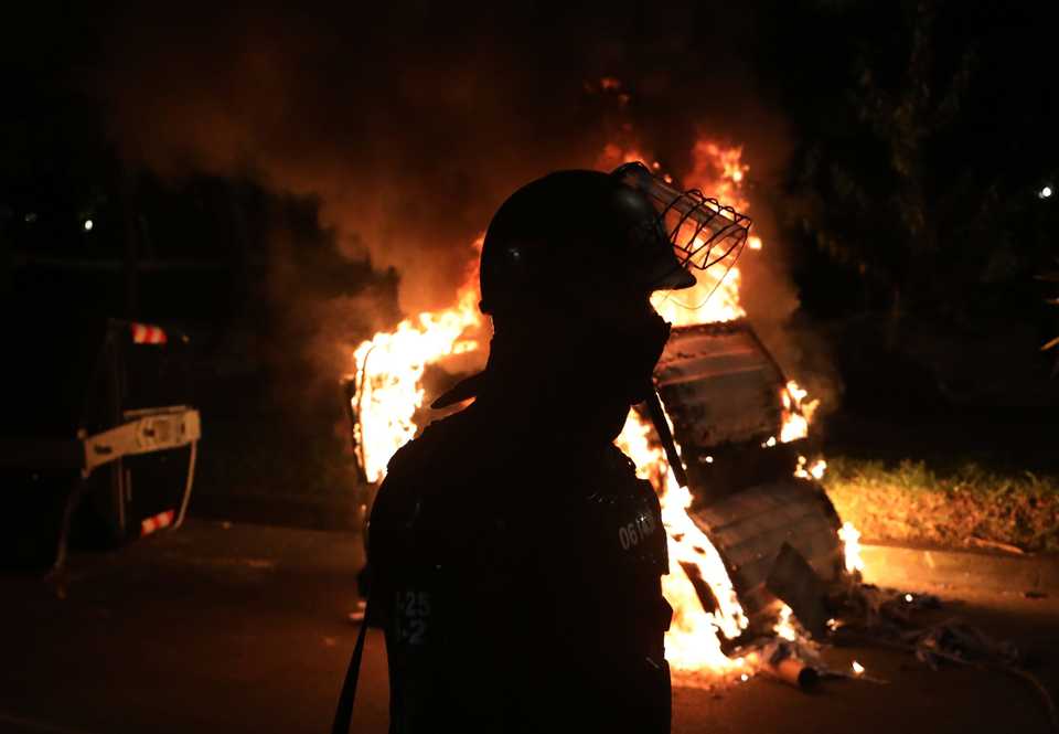 A police officer in riot gear stands behind a burning barricade during protests, in Bogota, Colombia, September 10, 2020.