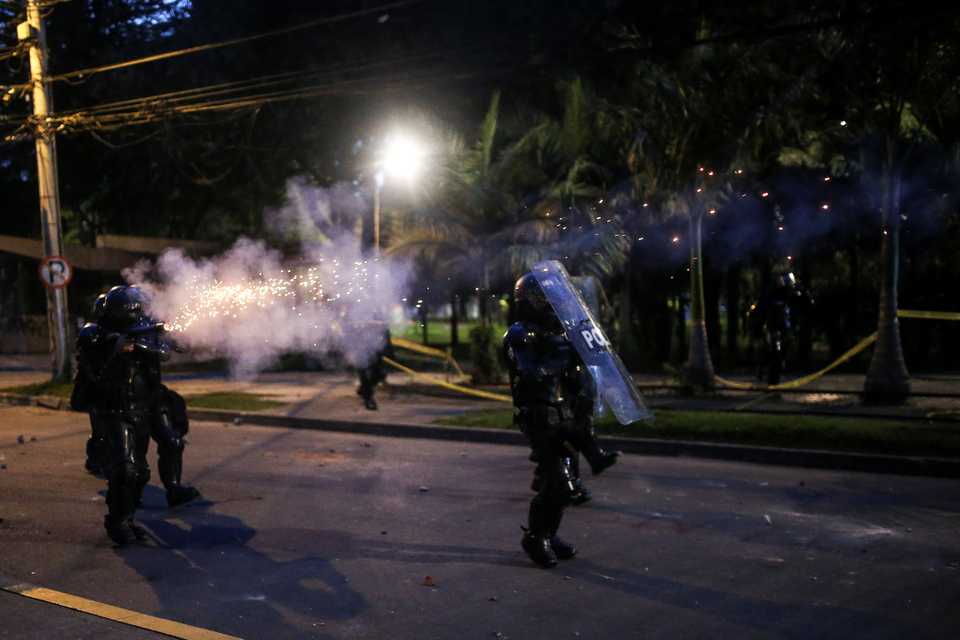 Police officers react as people protest after a man, who was detained for violating social distancing rules, died from being repeatedly shocked with a stun gun by officers, according to authorities, in Bogota, Colombia, September 10, 2020.