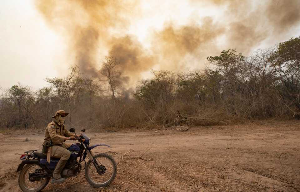 A firefighter rides a motorcycle past a burning area next to the Transpantaneira road at the Pantanal wetlands near Pocone, Mato Grosso state, Brazil, September 14, 2020.