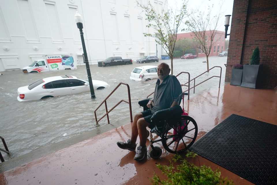 A man watches flood waters, Wednesday, Sept. 16, 2020, in downtown Pensacola, Fla.