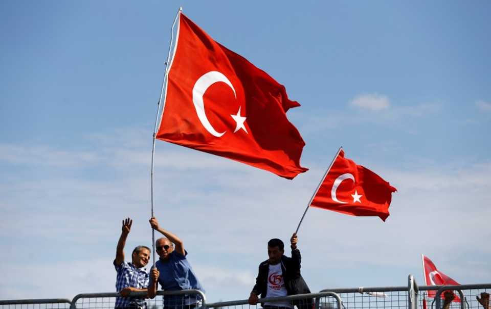 People wave Turkey's national flags as they arrive for a ceremony to commemorate the attempted coup on its first anniversary at the July 15 Martyrs Bridge (formerly called Bosphorus Bridge) in Istanbul, Turkey, July 15, 2017. 