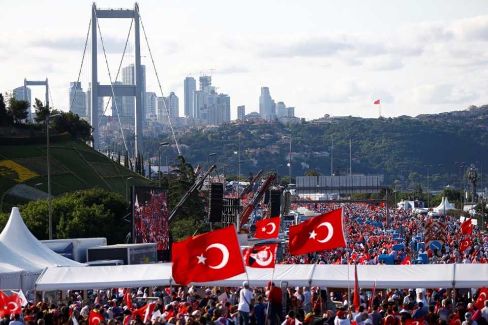 People wave Turkey's national flag as they arrive to attend the ceremony marking the first anniversary of the attempted coup at the July 15 Martyrs Bridge in Istanbul, Turkey on July 15, 2017.